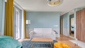 Ein modernes Wohnzimmer mit einer Couch, einem Couchtisch und einer Lampe. Eine Schiebetür führt in einen anderen Raum.