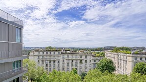 Un bâtiment moderne doté d’un balcon et offrant une vue sur un bâtiment historique en arrière-plan.