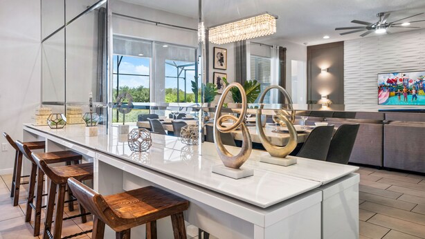 A modern kitchen with a large island, bar stools, and decorative items. - 12BR, BBQ Oasis, Game Room & Home Theater! (Davenport)