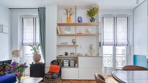 Una sala de estar moderna con una estantería central, un sofá, una mesa de comedor y una silla.