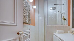 Baño con ducha, inodoro, lavamanos y toallero.