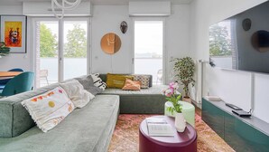 Un salón moderno con un sofá gris, una mesa de centro redonda y un televisor de pantalla plana montado en la pared.