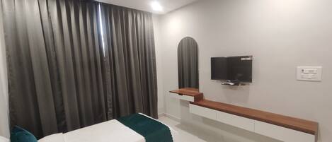 A modern bedroom with a bed, a TV mounted on the wall, and a wooden bench.