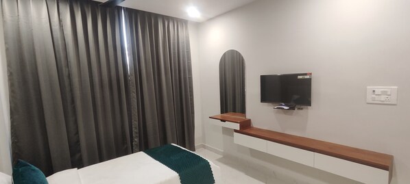 Un dormitorio moderno con una cama, un televisor montado en la pared y un banco de madera.