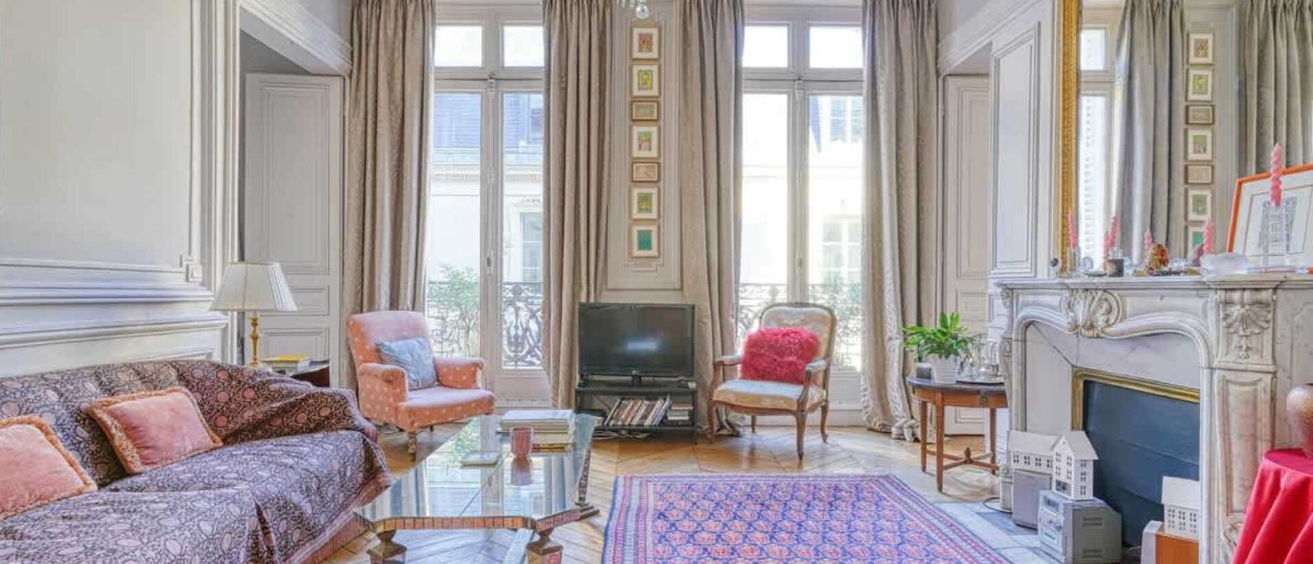 A spacious living room with a sofa, armchairs, a television, and a fireplace.