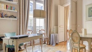 A room with a dining table, chairs, a bookshelf, and a painting on the wall. - Invalides - The Collector (Paris)