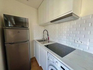 A compact kitchen with a built-in refrigerator, a sink, and a washing machine.