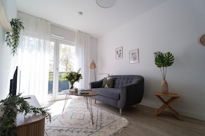 A modern living room with a grey sofa, a coffee table, and a side table with a plant.