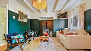 A cozy living room with a sofa, chairs, a fireplace, and a television. - Left Coast Hideaway - New Listing! (Cannon Beach)
