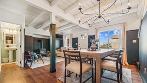 A spacious living room with a high ceiling, a fireplace, and a dining area with a large table and chairs. - Left Coast Hideaway - New Listing! (Cannon Beach)