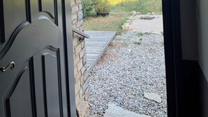 A doorway leading to a gravel path with a view of a green field and distant hills. - Provencal house with swimming pool in the heart of nature on 5000m2 of land (Montélimar)
