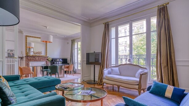 Amplia sala de estar con sofá, sillones, una mesa de centro y chimenea.