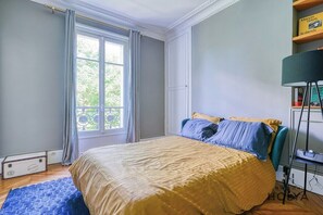 Una camera da letto con un letto, una finestra con tende, una libreria e una lampada da terra.