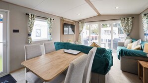A compact living space with a dining table, cushioned seating, and a large window offering a view of the outside. - Host & Stay | Grange (Morecambe)