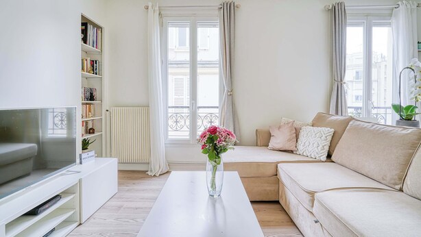 A living room with a sofa, a coffee table, a TV, and a bookshelf. - Ternes district - The Dreamer (Paris)