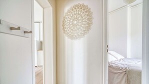 A bedroom with a bed, a wall decoration, and a door leading to another room. - Ternes district - The Dreamer (Paris)