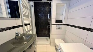 Ein kleines Badezimmer mit Waschbecken, Toilette und Duschbereich.