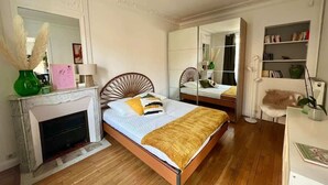 Ein Schlafzimmer mit einem Bett, einem Kamin, einem Spiegel und einem Bücherregal.