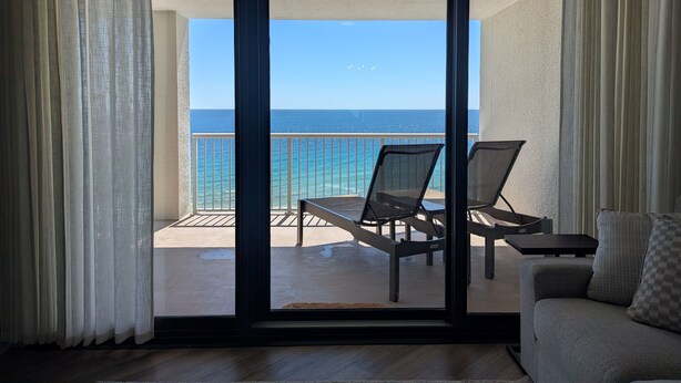 A balcony with a view of the ocean, a sofa, and two chairs. - Summer House 1104A - Fully Renovated Inside and Out in 2026! (Orange Beach)