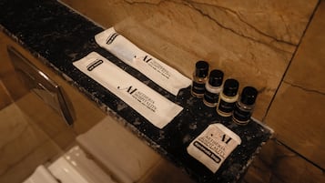 A hotel reception counter with amenities including a soap dispenser, a bottle of lotion, and a bottle of shampoo.