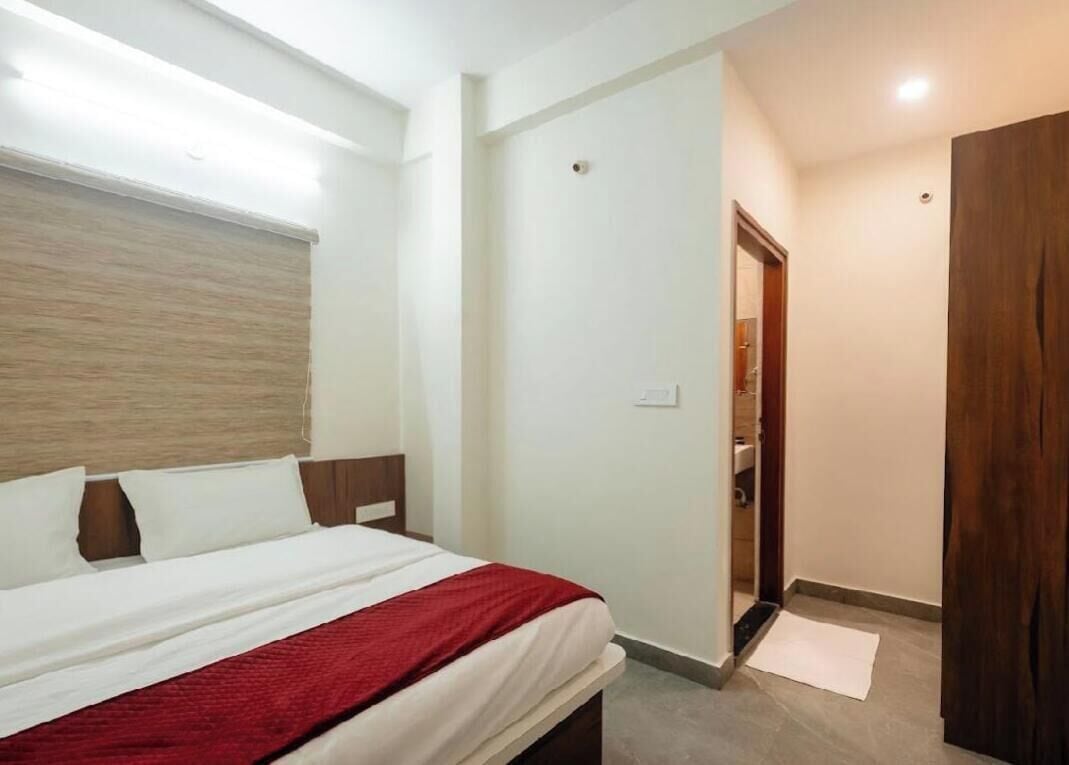 Una habitación de hotel con una cama, cabecera de madera, una puerta y un ventanal pequeño.