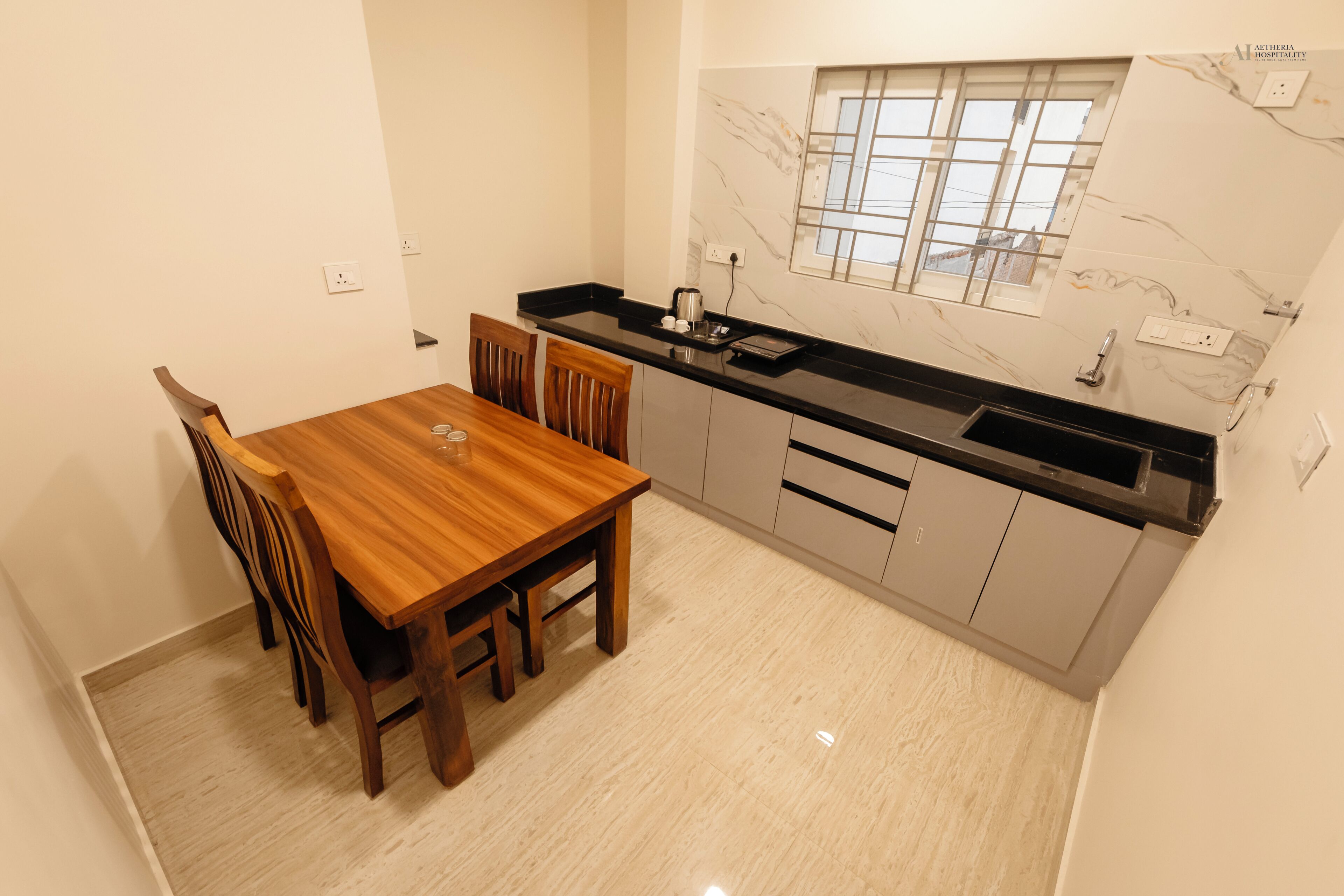 A compact kitchen with a wooden dining table and chairs, a black countertop, and a window with a view.