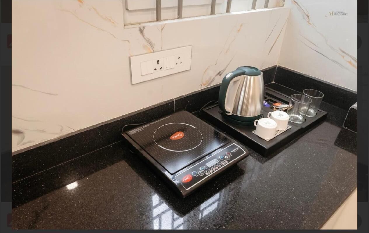 Eine moderne Küche mit integriertem Induktionskochfeld, einem Wasserkocher und einer Kaffeemaschine auf einer schwarzen Arbeitsfläche.