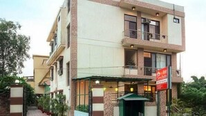 Un edificio de varios pisos con techo plano, un balcón en el segundo piso y un toldo verde sobre la entrada.