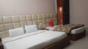 Un dormitorio con una cama grande, una cama más pequeña y una mesita de noche.