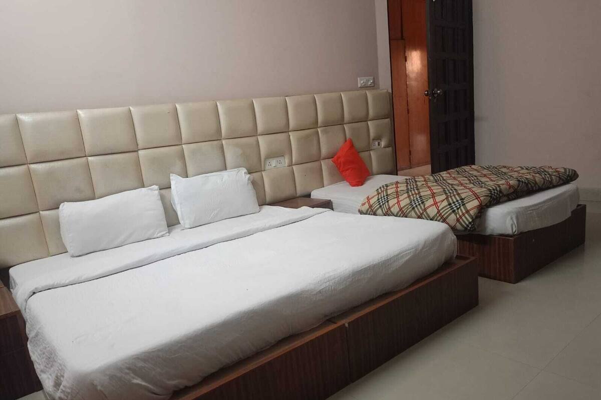 A bedroom with a large bed, a smaller bed, and a nightstand.