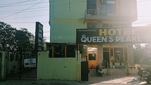 Un edificio de dos pisos con un letrero que dice 'Queen's Pearl Hotel'.