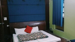 Un dormitorio con una cama grande, un cabecero de madera, una ventana con cortinas azules y una pared verde.
