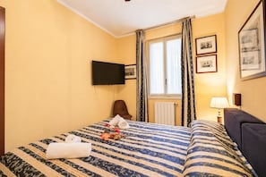 A hotel room with a bed, a flat-screen TV, a window with curtains, and framed pictures on the wall. - Alice Suite Terrace, Lake View & Park (Gardone Riviera)