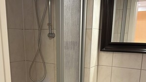 Un baño con ducha de vidrio, un lavabo blanco y un espejo sobre el lavabo.