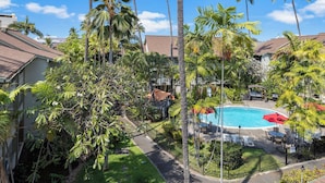 A pool area surrounded by palm trees and a clear blue sky.