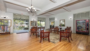 A spacious room with wooden flooring, a chandelier, and a Coca-Cola refrigerator.