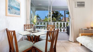 A balcony with a dining table, chairs, and a bed.