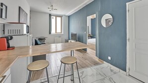 Une cuisine moderne avec un plan de travail en bois, deux tabourets, un four à micro-ondes et une machine à café.