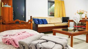 A bedroom with a bed, a wooden dresser, a sofa, a television, and a table with a vase of flowers. - Nafpaktos Cozy Nest, Homely Vibes near the Beach (Paleopanagia)