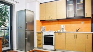 A compact kitchen with a stainless steel refrigerator, white stove, and wooden cabinets. - Nafpaktos Cozy Nest, Homely Vibes near the Beach (Paleopanagia)