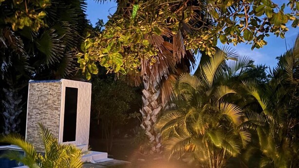A well-lit outdoor area with a fire pit, seating, and a stone structure. - Kooteja Aurora Coronado Nature with Private Pool (Las Lajas)