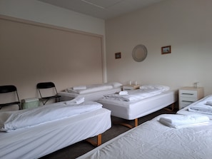 A hotel room with two beds, a small table, chairs, and a wall-mounted mirror.