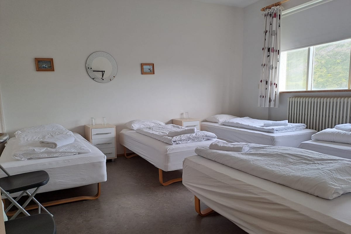 A hotel room with three beds, a desk, and a chair.