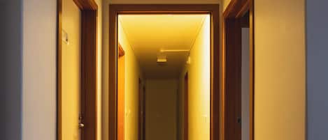 A hallway with wooden flooring and doors on both sides leading to rooms.