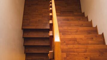 Una escalera de madera con barandilla que asciende en un espacio reducido.