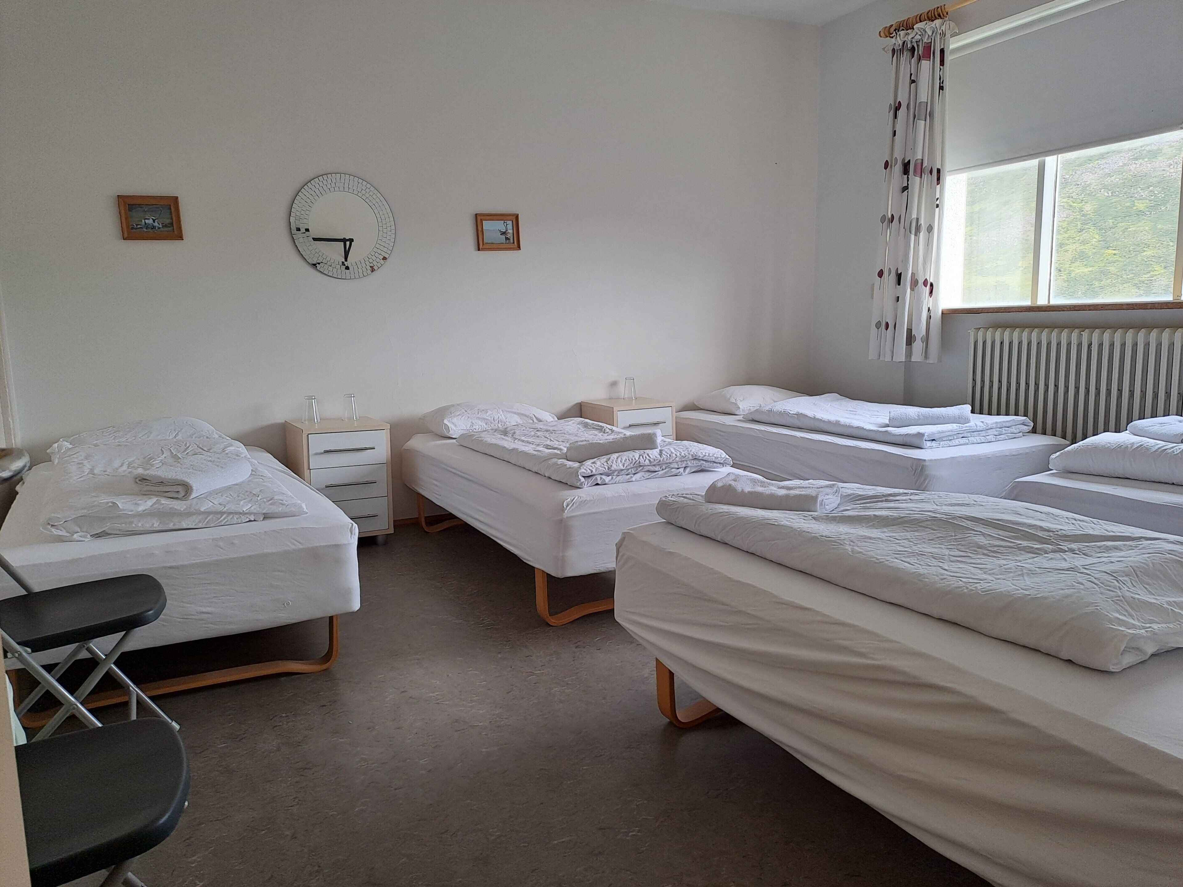 A hotel room with three beds, a desk, and a chair.