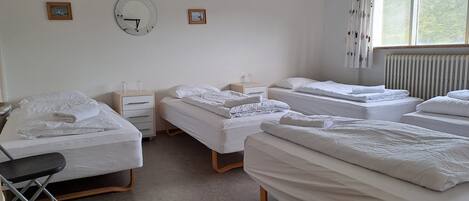 A hotel room with three beds, a desk, and a chair.