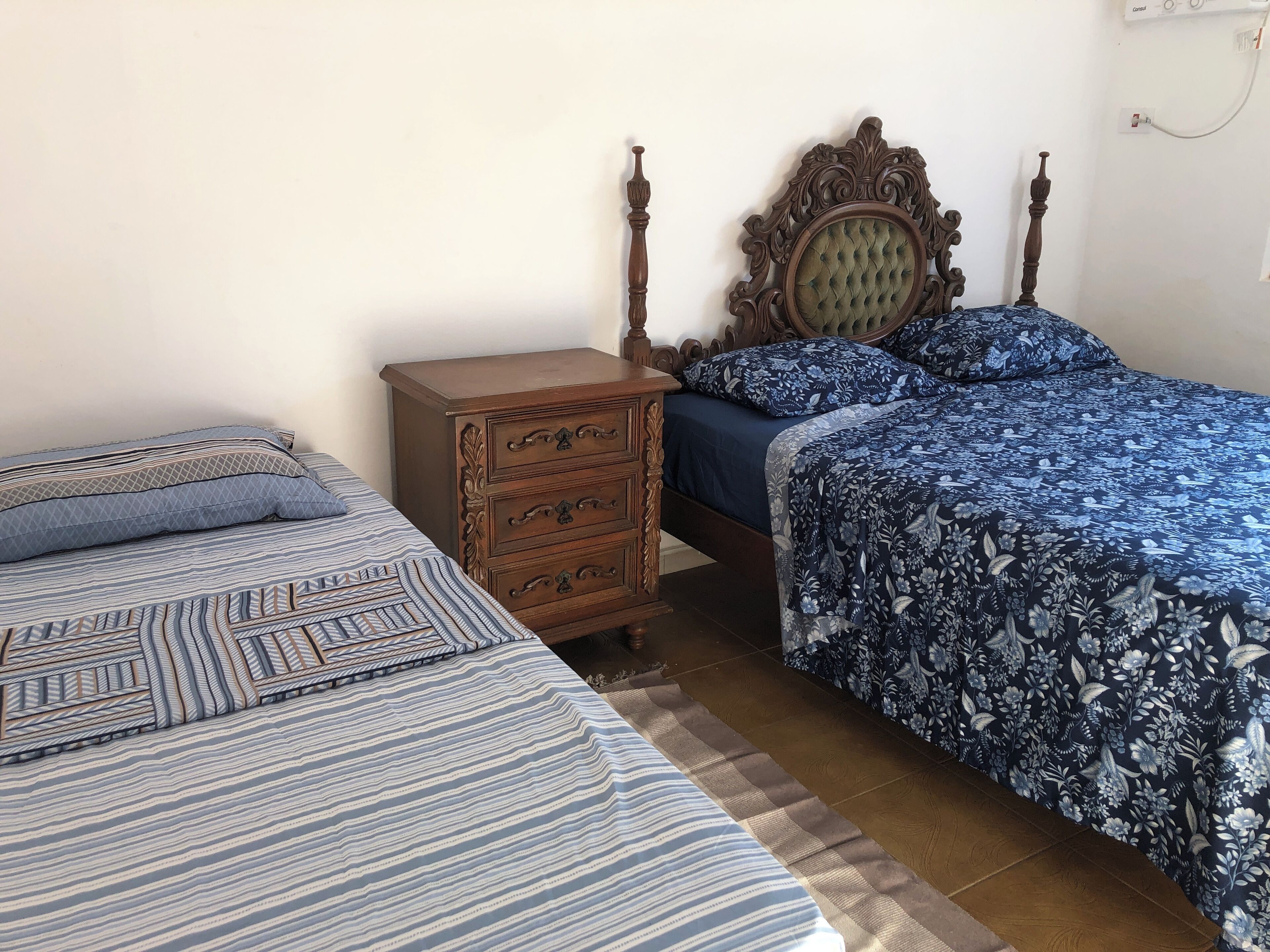 A bedroom with two beds, a wooden dresser, and a decorative headboard.