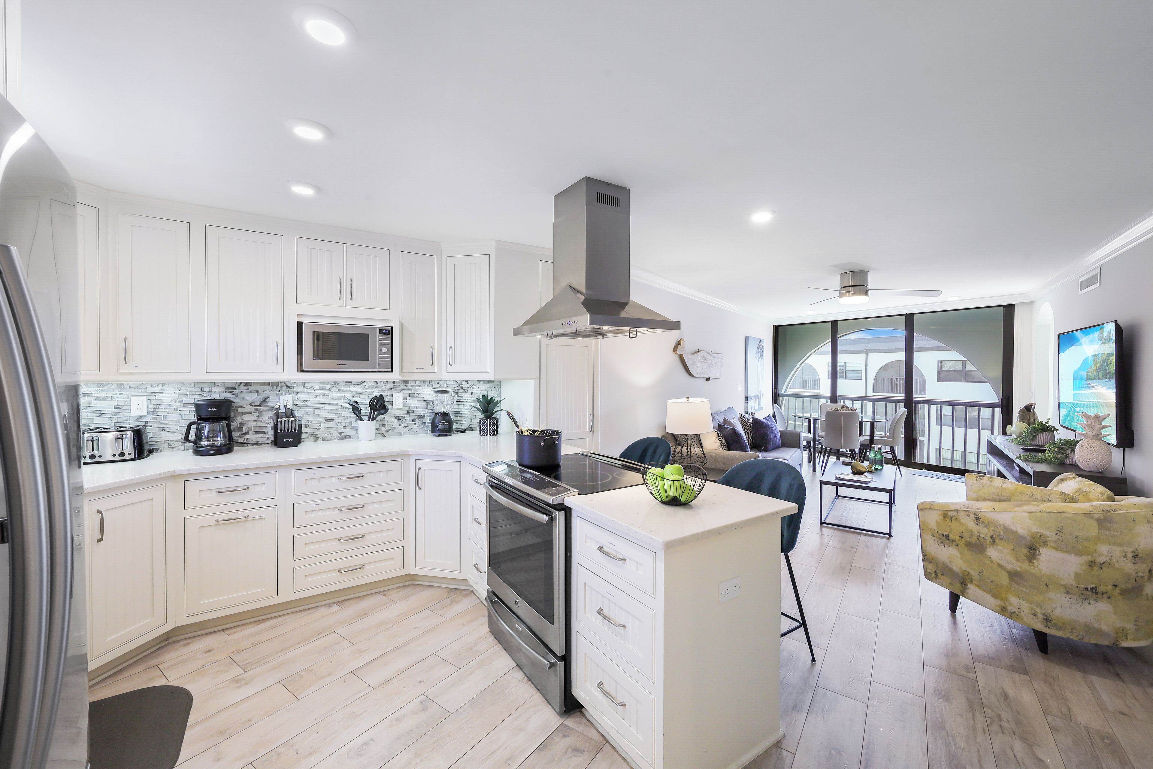 A modern kitchen with white cabinets, a built-in microwave, and a stainless steel range hood.
