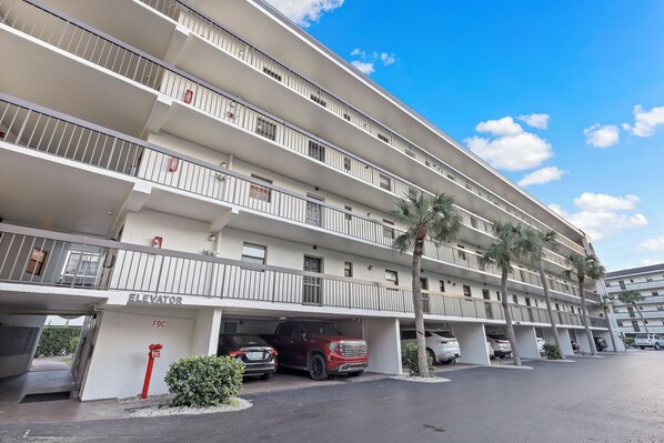 A multi-story hotel with a parking garage, multiple balconies, and palm trees.